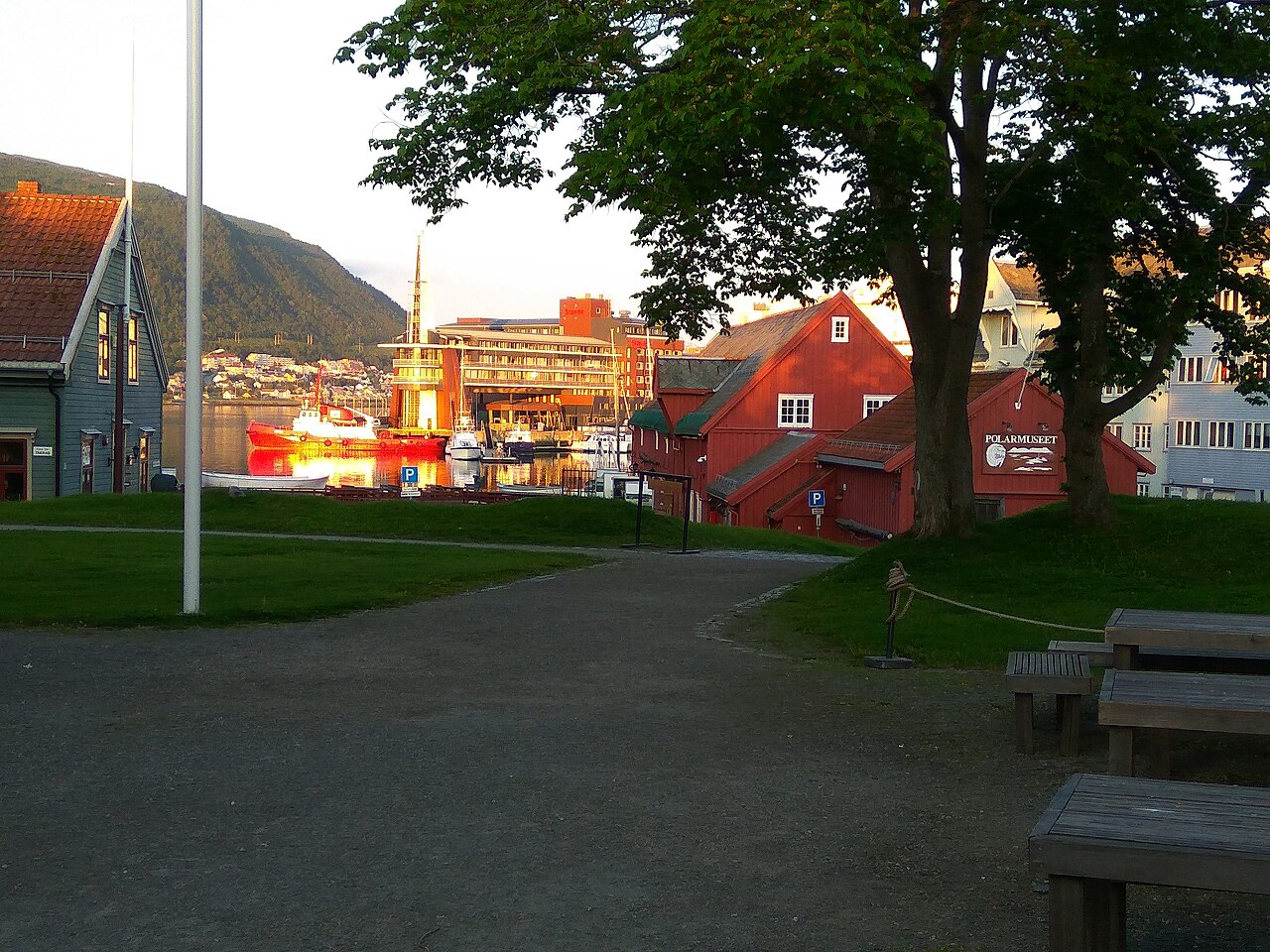 The red wooden Polar Museum buildings by the harbour in Tromsø seen across a green lawn