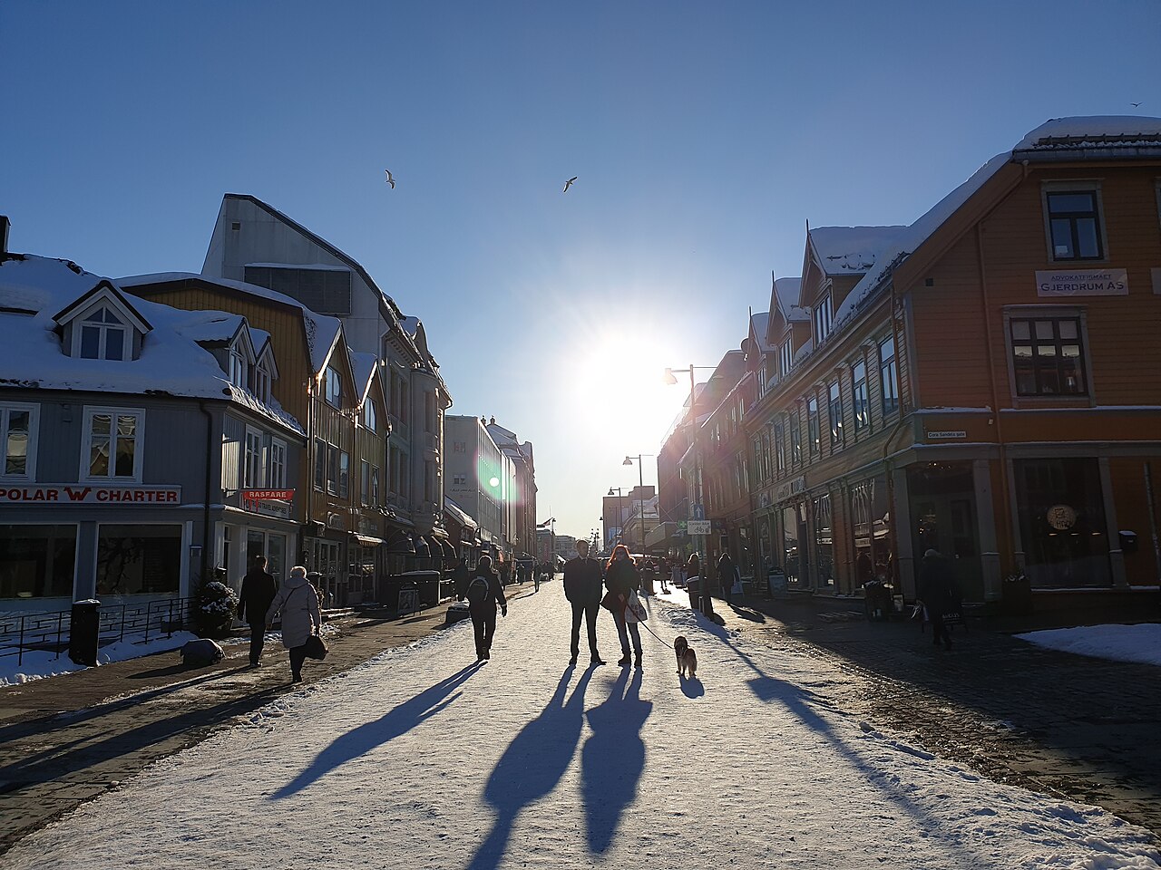 Low winter sun over Storgata, the main pedestrian street in Tromsø, with people walking